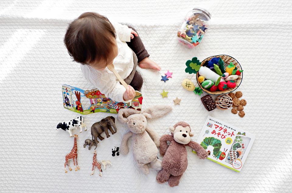 A baby exploring soft toys and books in the infant room